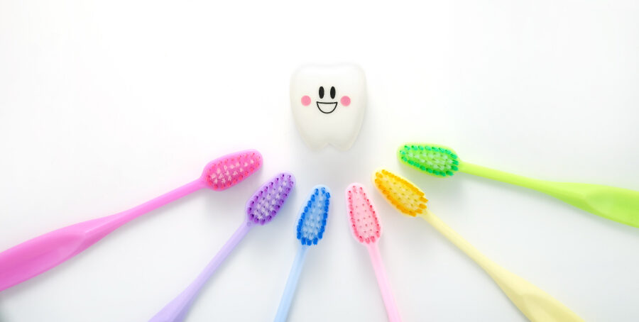 A rainbow of toothbrushes point to a smiling tooth to symbolize choosing a dentist