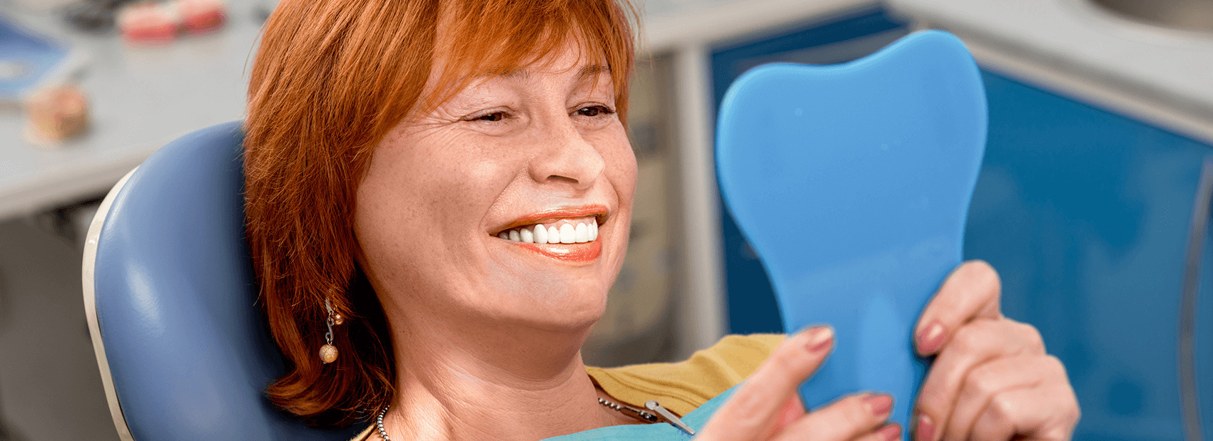 woman at the dentist smiling into a mirror