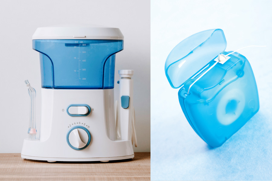 Closeup of a water flosser next to a blue container of string floss that will improve oral health