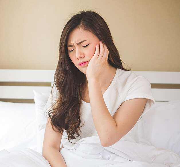 woman holding her jaw in pain