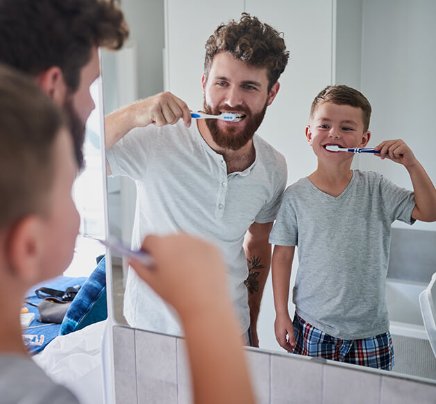 father and son brushing their teeth together