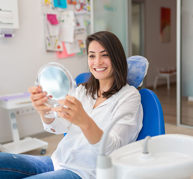 woman examining her smile in a mirror