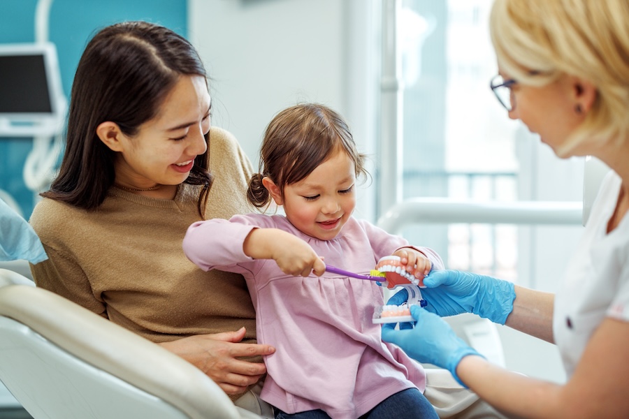 woman holding child in lap at dentist, children's dental health